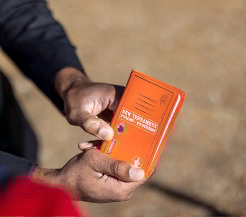Man holding a bible showing it to someone