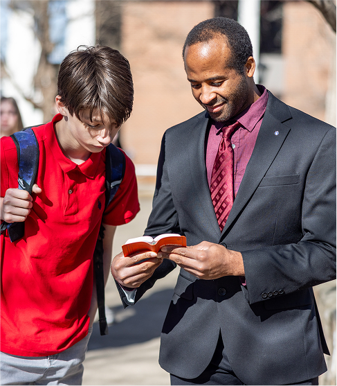 Man showing student a bible outside