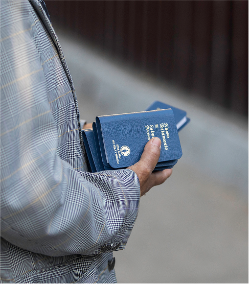 Stack of bibles in a mans hands being handed out